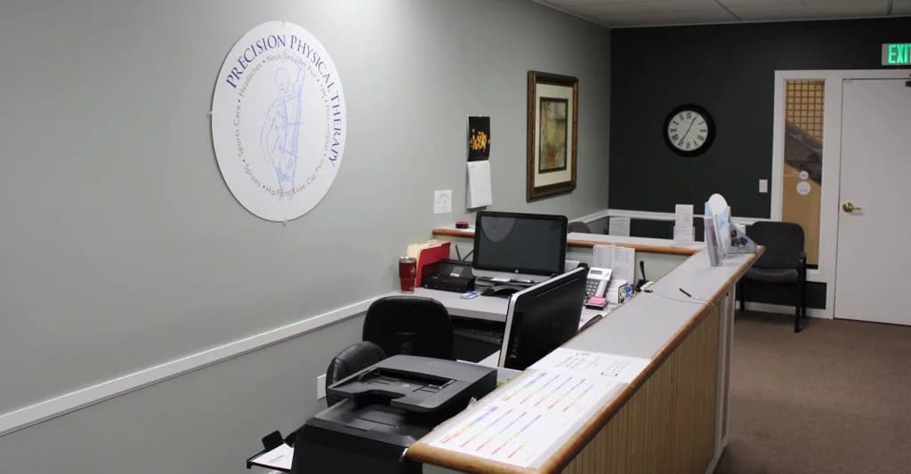 The front desk at Precision Physical Therapy, with the clinic's round logo sign on the wall